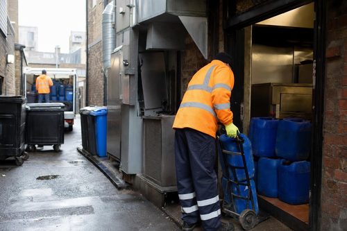 Sealed oil containers at a London takeaway rear entrance being lifted onto a sack truck