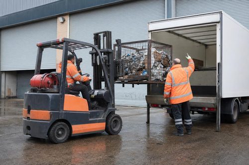 Forklift loading industrial waste into a lorry at a London industrial estate