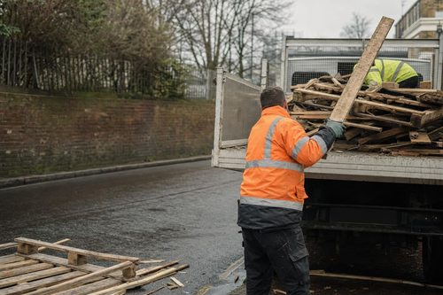 Timber offcuts and pallets being loaded into a tipper in London